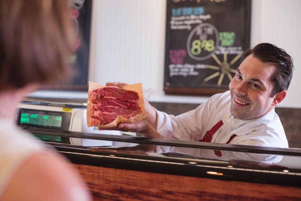 Mm maple ridge smiling butcher shows steaks to customer a